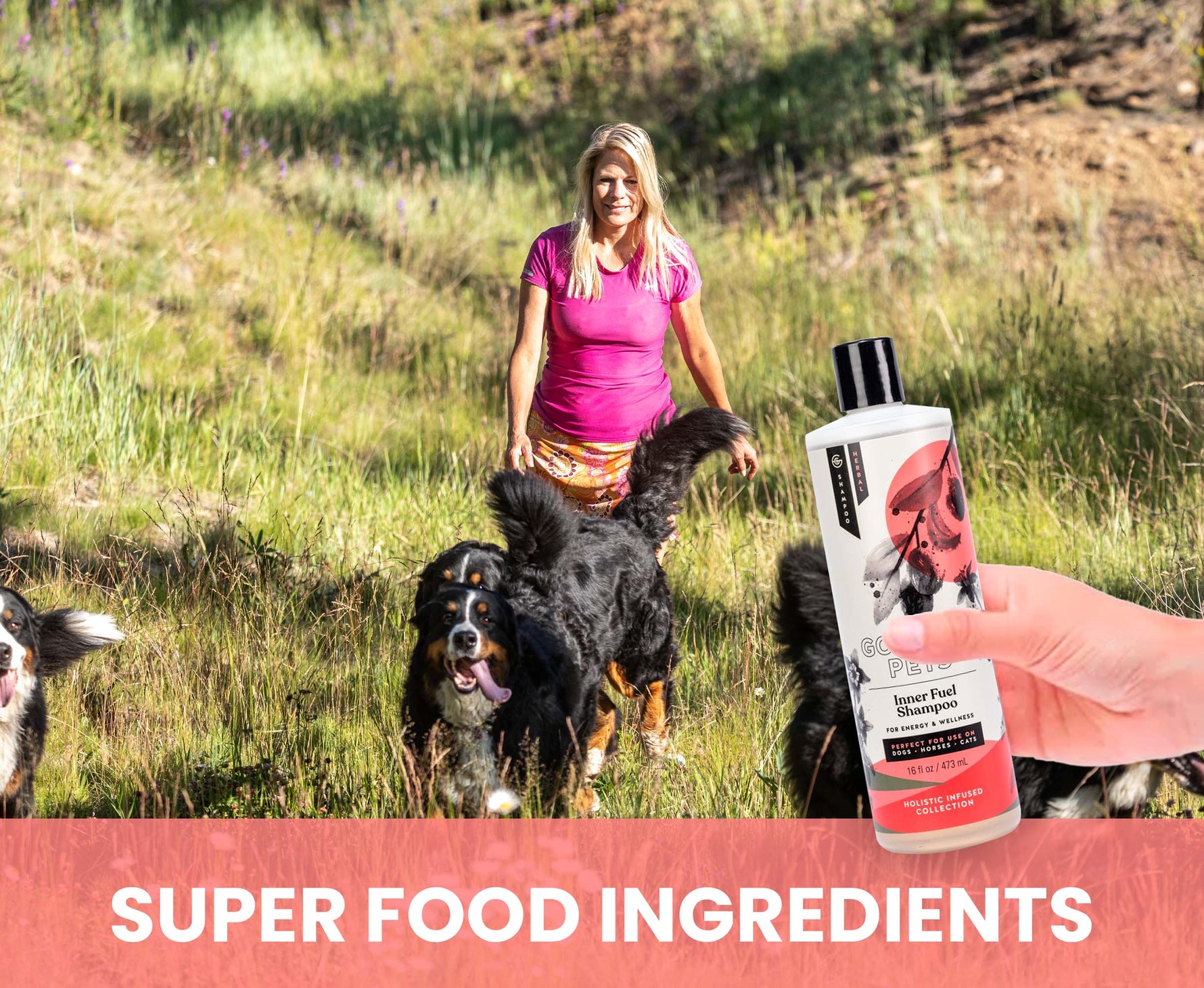 Woman walking dogs in a field with a bottle of dog shampoo labeled 'Super Food Ingredients'.