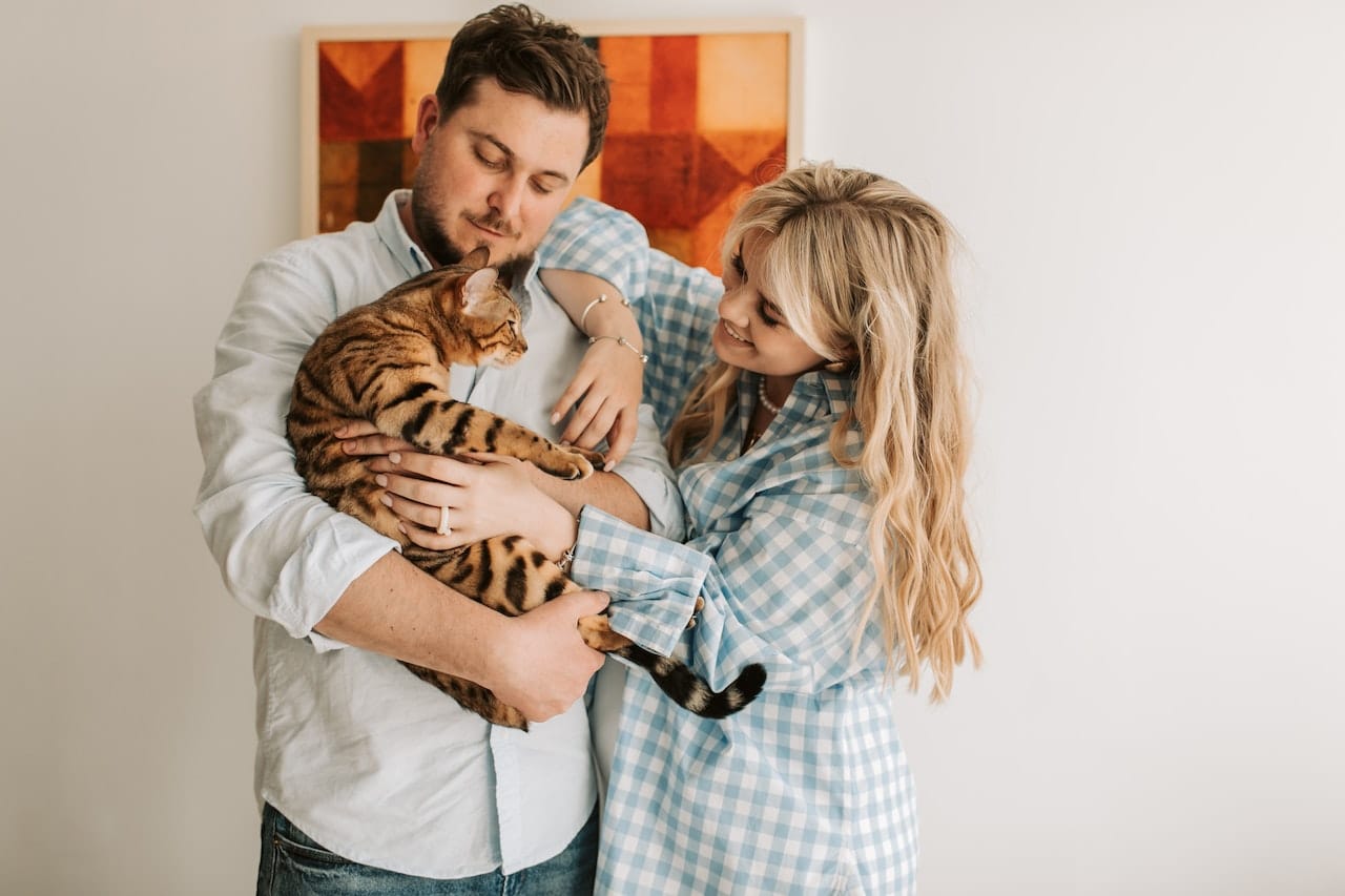 A young couple holding on to a stripped cat