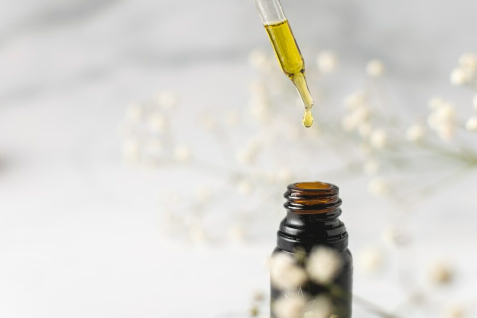 a dropper full of essential oils dripping into an open vial