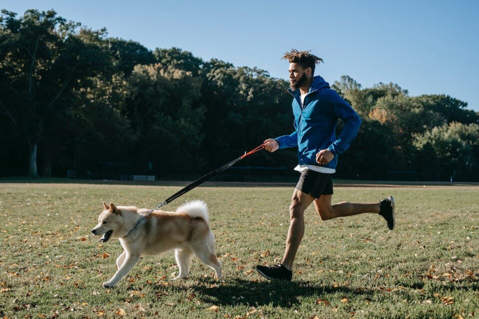 A man running with his dog in a field