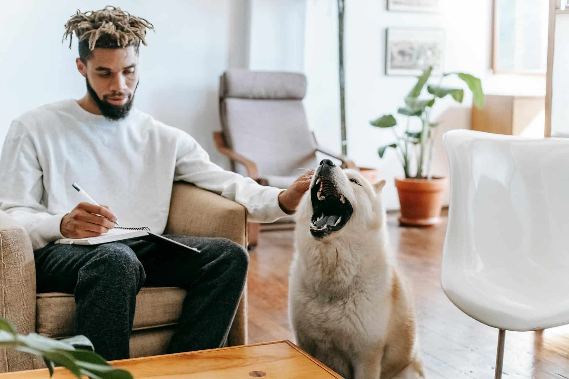 man caressing his dog while taking notes