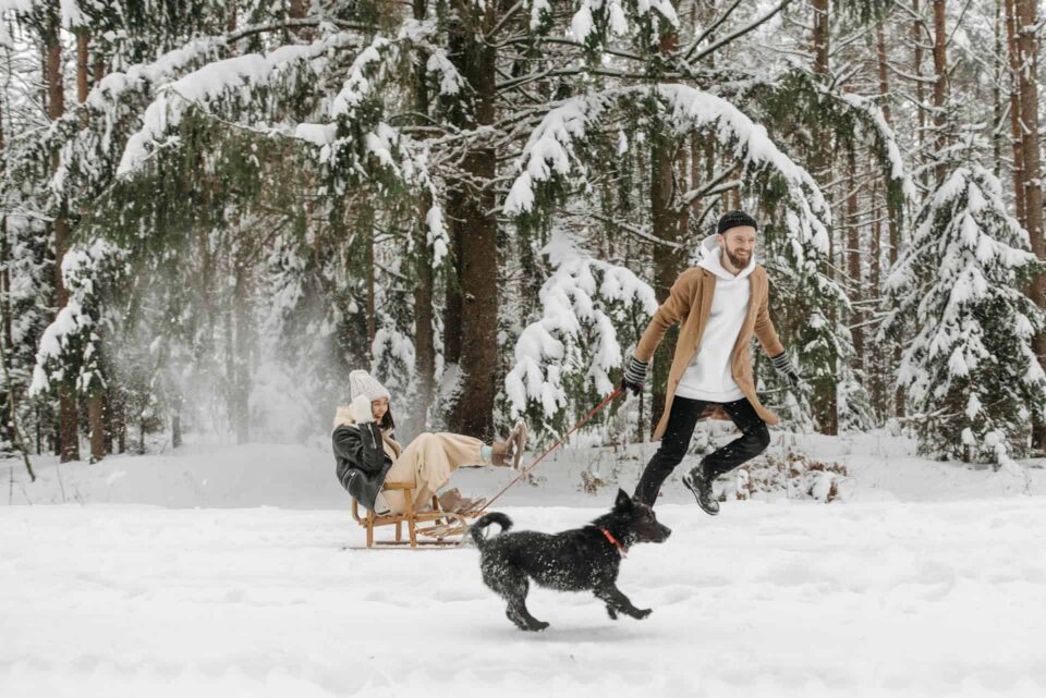 a man pulling a woman on a sleigh