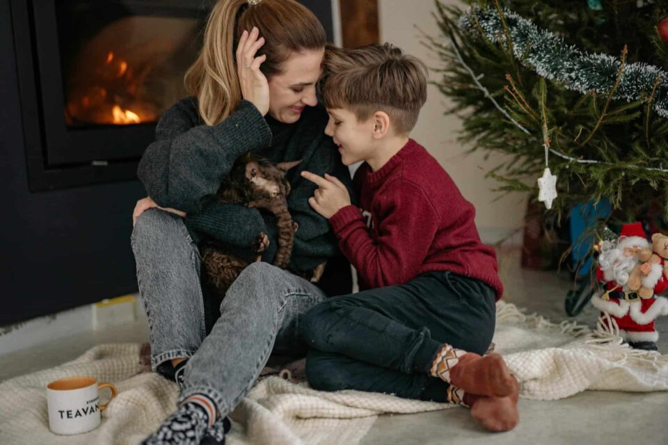 mother holding a cat with her son sitting by the fireplace